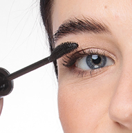 Žena si nanáša maskaru kefkou, dodáva mihalniciam objem a zdokonaľuje očný make-up.